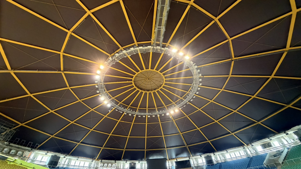 Domed ceiling of Fengshan Gymnasium with dark micro-perforated metal acoustic panels installed between yellow radial steel trusses